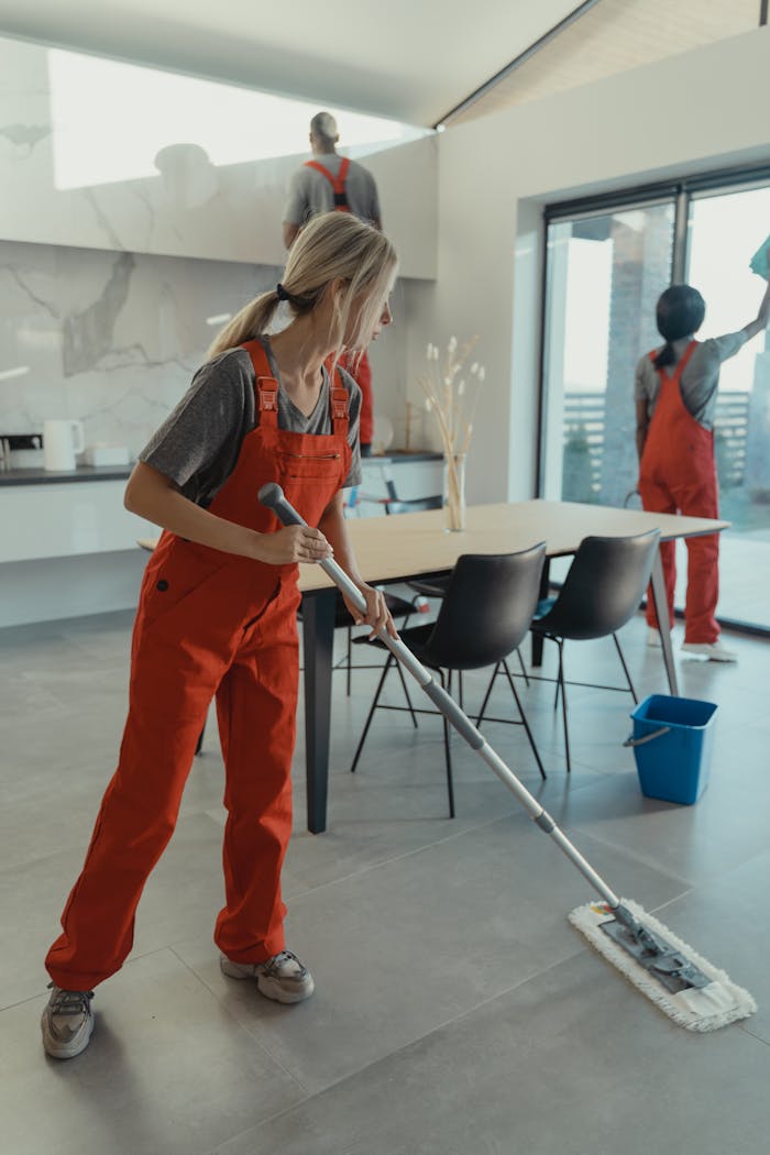 services-03 Cleaning team in red overalls mopping and sanitizing a modern home interior.