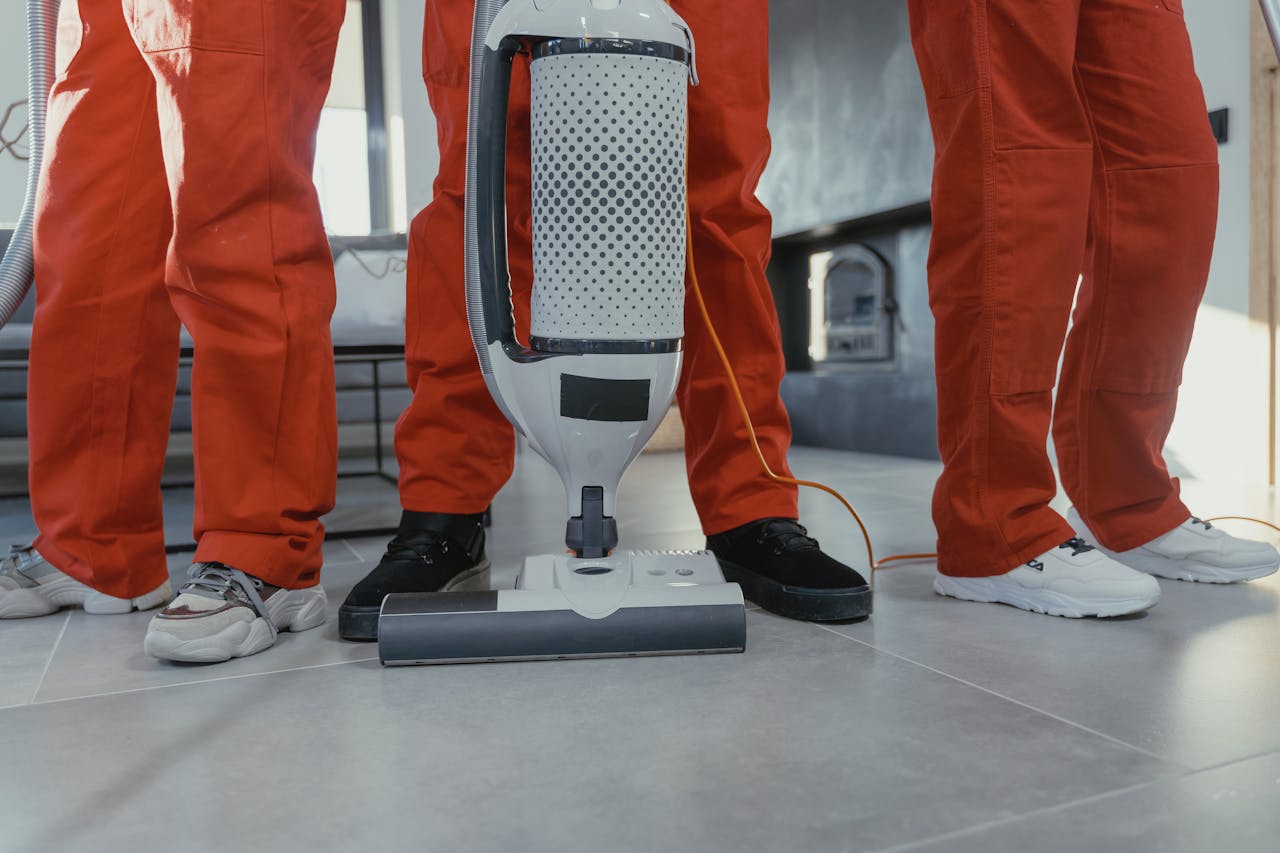 hero-img-02 Team of professional cleaners in red uniforms using a vacuum cleaner indoors.