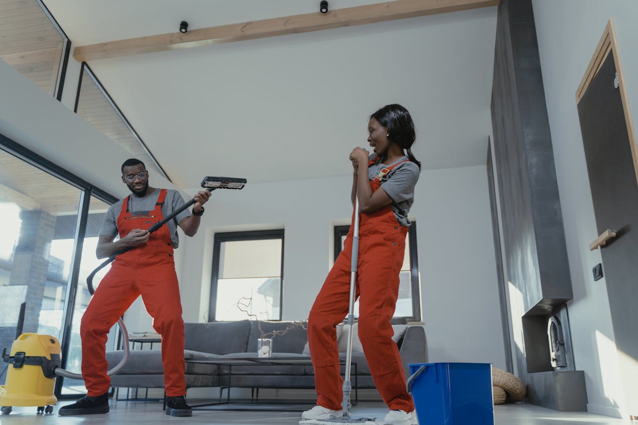 about-01 Two adults in vibrant coveralls cleaning a modern home interior, enjoying work.